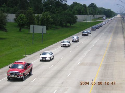1984 Chevrolet Blazer - A long line of vehicles travels down a highway, suggesting a funeral procession.