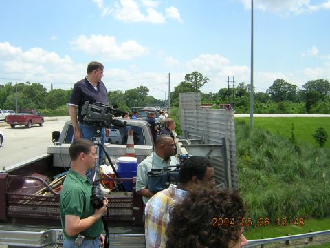 1984 Chevrolet Blazer - Media personnel are positioned in the bed of a pickup truck, filming a procession on a sunny day.