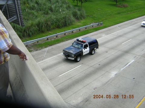 1984 Chevrolet Blazer - A police SUV drives down the highway, with another vehicle visible in the distance.