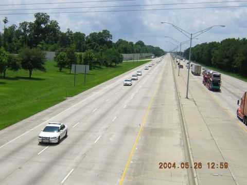 1984 Chevrolet Blazer - A procession of vehicles travels down a multi-lane highway under a cloudy sky.