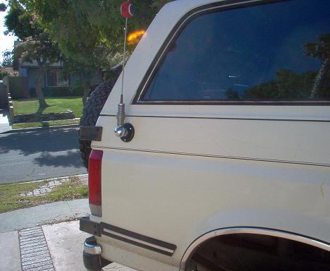 1988 Ford Bronco - Close-up of the rear side of a white SUV, showing the spare tire and antenna.