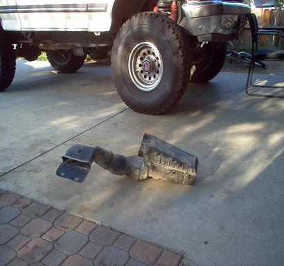 1988 Ford Bronco - Air intake system part removed from a Ford Bronco, lying on a concrete driveway.