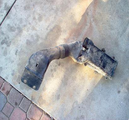 1988 Ford Bronco - A used air intake hose and resonator box lies on a concrete surface.