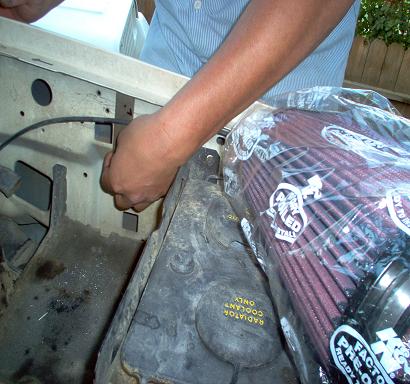 1988 Ford Bronco - A person is installing a new K&N air filter into the engine bay of a vehicle.