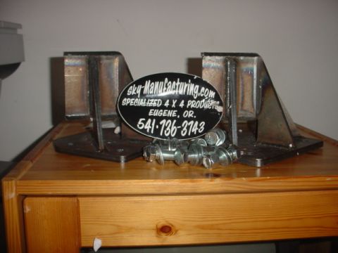 1988 Ford Bronco - Metal lift brackets and hardware are displayed on a wooden surface.