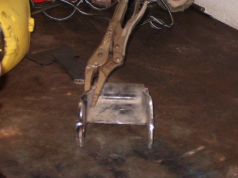 1988 Ford Bronco - A metal part is secured by vise grips on a workbench, with a yellow object and wires visible in the background.