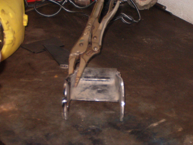 Metal part held by vise grips on a workbench