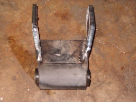 1988 Ford Bronco - Close-up of a suspension shackle part, showing a rubber bushing and welded metal components.