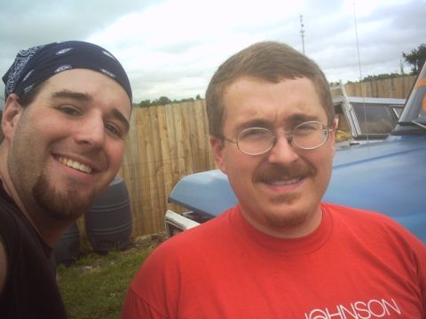 1991 Ford LTD Crown Victoria - Two men pose for a photo in front of a blue vehicle, with a wooden fence in the background.