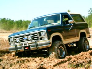 1985 Ford Bronco - This 1985 Ford Bronco is captured in a three-quarter front view while navigating a dirt terrain.