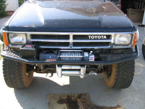 1986 Ford F-150 - This black Toyota truck features a prominent winch and an aftermarket bumper. The grille design suggests a 1989 model year.