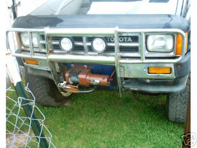 1986 Ford F-150 - A Toyota truck's front end is visible, equipped with a brush guard and a winch.