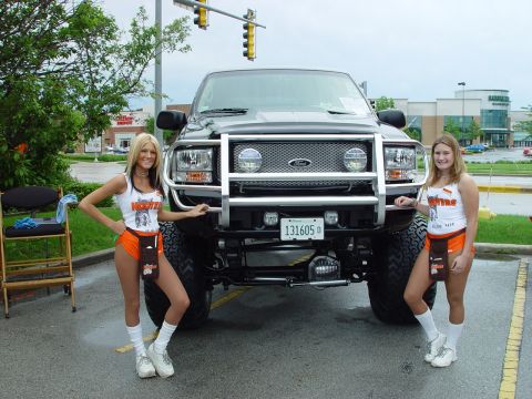 2001 Ford Excursion - A black 2001 Ford Excursion is shown with a prominent bull bar and two women posing beside it.