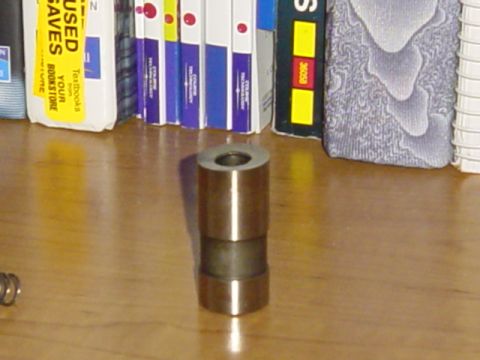1989 Ford Bronco - A close-up of a metal valve stem seal sits on a wooden surface, with books visible in the background.