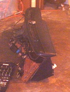 1991 Ford LTD Crown Victoria - Dark, low-resolution shot of a dashboard assembly removed from a car and set on a concrete garage floor, resting on its side with the HVAC…