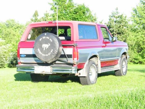 1995 Ford Bronco - The rear view of a red and silver Ford Bronco, showing its spare tire and two-tone paint scheme.