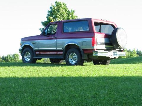 1995 Ford Bronco - This two-tone 1995 Ford Bronco is seen from the rear, parked on a sunny, grassy slope.