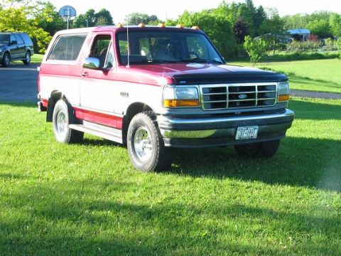 1995 Ford Bronco - 1995 Ford Bronco with a two-tone red and white paint scheme sits on a grassy lawn.