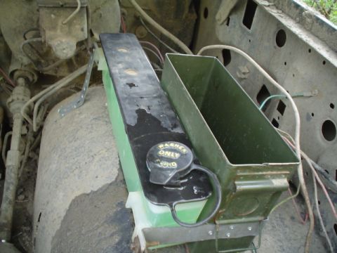 1981 Ford Bronco - A green windshield washer reservoir with a black lid and yellow 'WASHER FLUID ONLY' cap sits mounted alongside an empty green sheet-metal b…