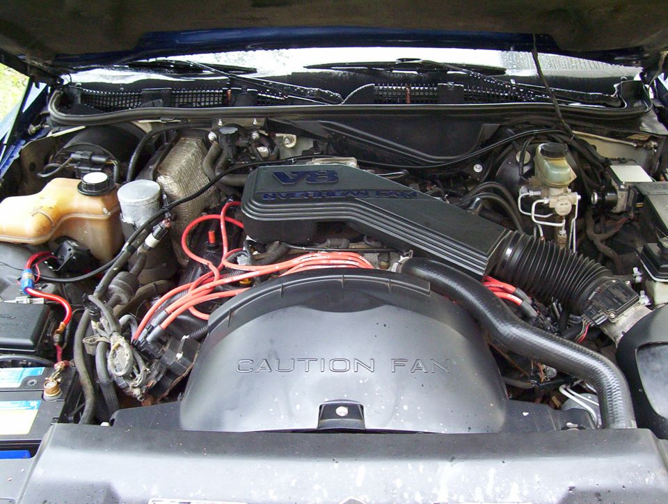 Blue Ford Crown Victoria engine bay with V8 engine cover and "CAUTION FAN" shroud