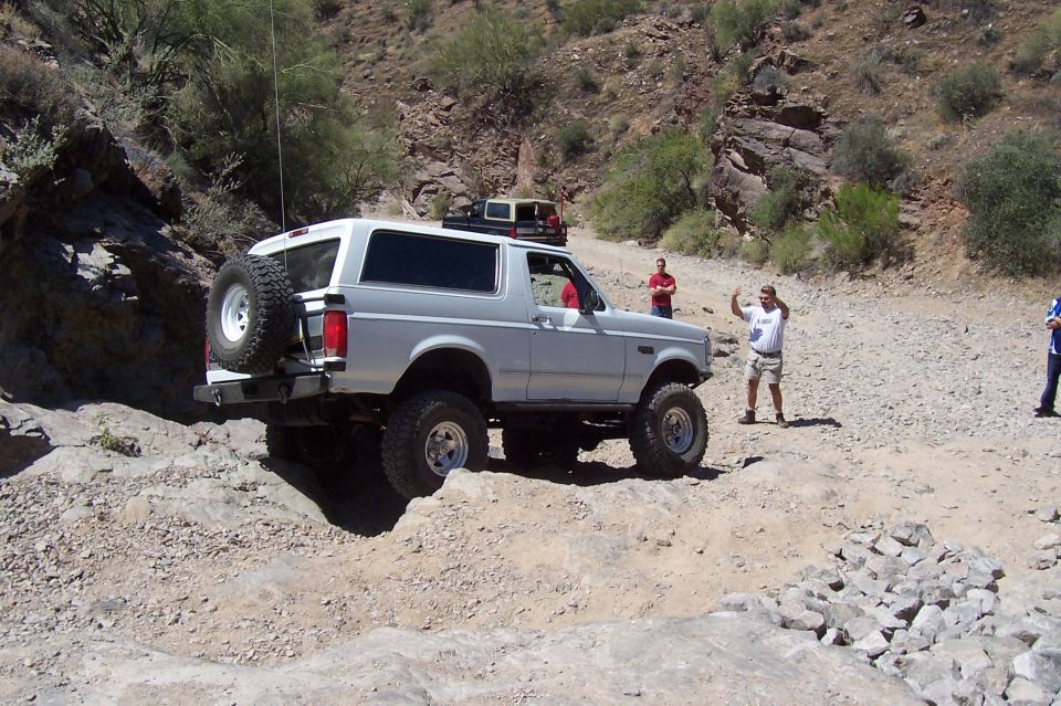 White 1992 Ford Bronco with spare tire on rear, navigating rocky terrain