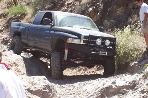 1992 Ford Bronco - A lifted black pickup truck navigates a challenging rocky terrain on an off-road adventure.