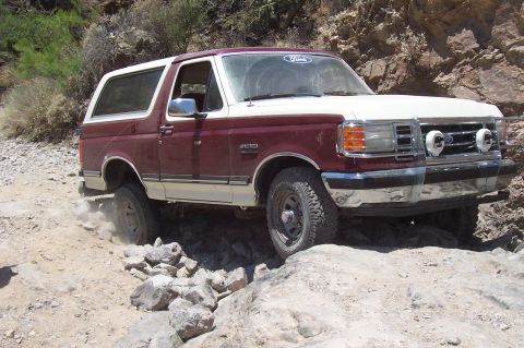 1992 Ford Bronco - Ford Bronco driving over rocks in a desert canyon.