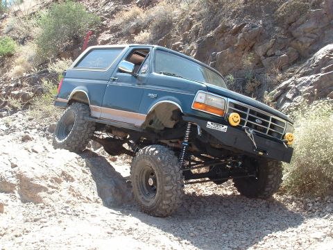 1990 Ford Bronco - This 1990 Ford Bronco is tackling a tough, rocky trail with its suspension and tires clearly visible.