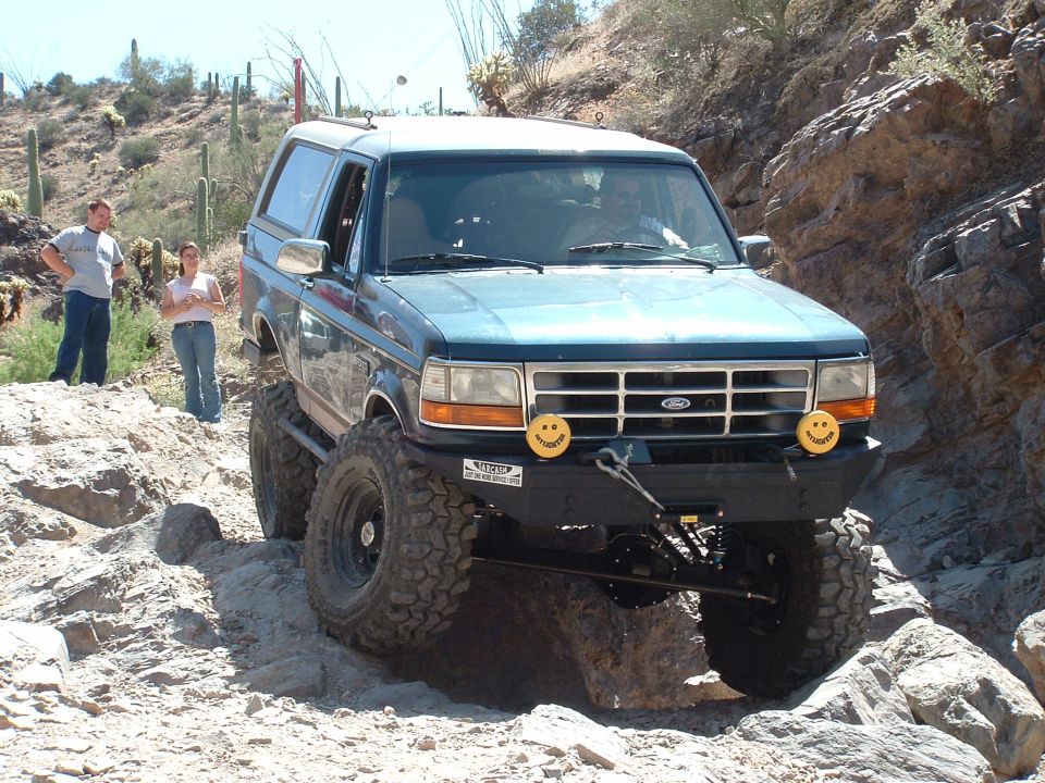 Blue SUV with large tires navigating a rocky desert trail