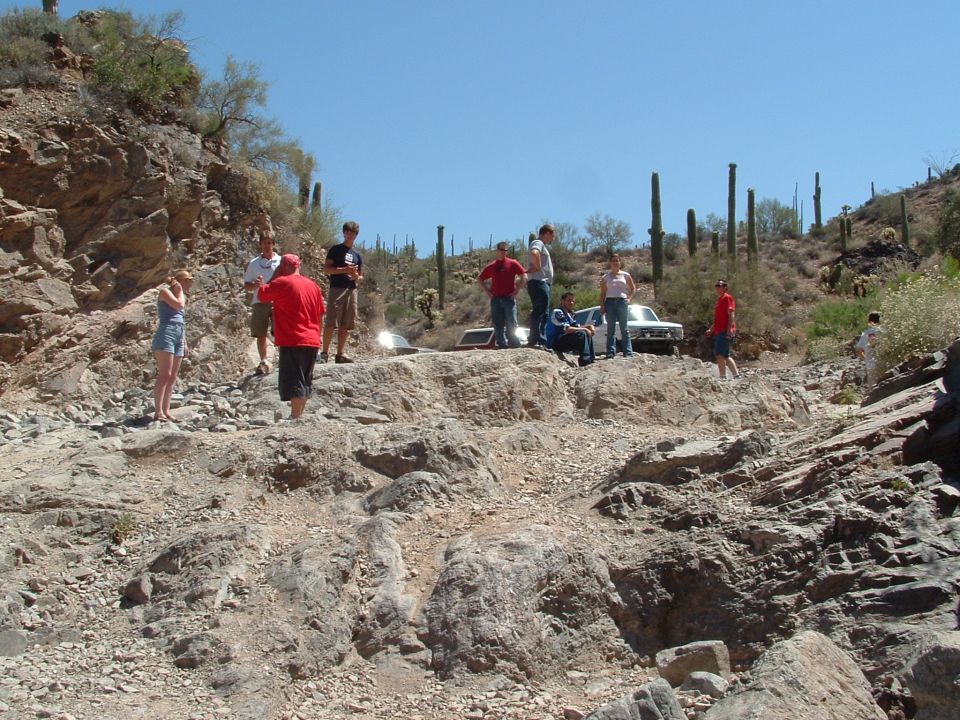 White 1990 Ford Bronco parked on a rocky incline with people around it