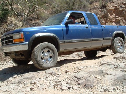 1990 Ford Bronco - Blue Dodge Dakota pickup truck navigating a rocky trail.