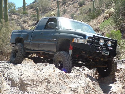 1990 Ford Bronco - Modified Dodge Ram 2500 navigating a rocky trail with lifted suspension and off-road tires.