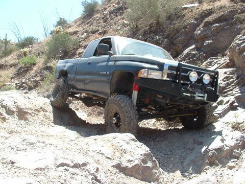 1990 Ford Bronco - A modified pickup truck tackles a challenging rocky terrain during an off-road excursion.