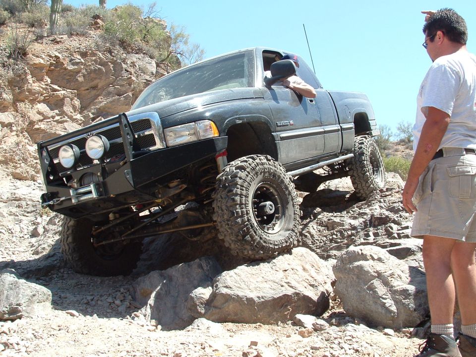 Black pickup truck with off-road tires navigating rocky terrain
