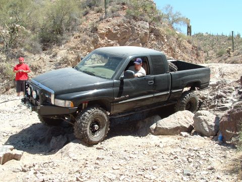 1990 Ford Bronco - Off-roading in a black Dodge Ram pickup truck on a rocky desert trail.