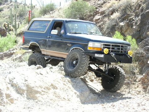 1993 Ford Bronco - This lifted Ford Bronco navigates a challenging rocky terrain, its off-road capabilities.