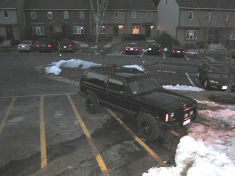 2000 Jeep Liberty - A black Jeep Cherokee XJ is parked in a lot with snow on the ground and apartment buildings in the background.