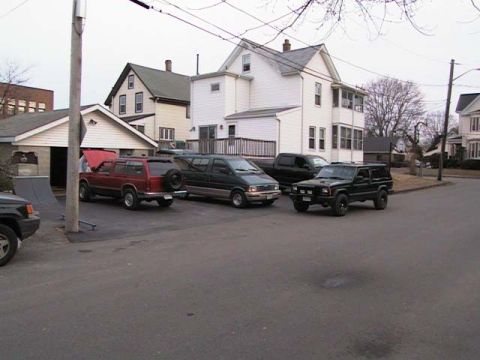 2000 Jeep Liberty - Multiple SUVs and a van are parked on a residential street in front of houses.