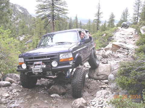 1994 Ford Bronco - Ford Bronco tackling a difficult off-road path with another vehicle visible in the distance.
