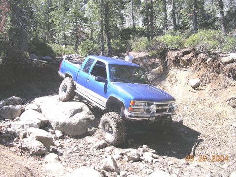 1994 Ford Bronco - Pickup truck is shown off-roading on a rocky, wooded trail.