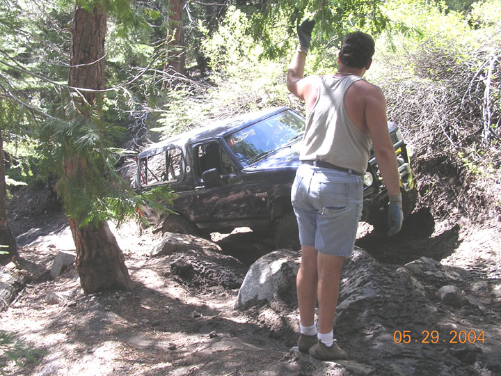 Black SUV with a removable top navigating a rocky, muddy trail