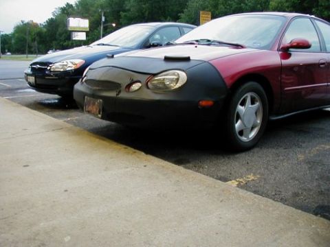 1997 Ford Taurus - Two cars, a red Ford Taurus and a blue sedan, are parked side-by-side.
