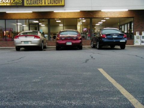 1997 Ford Taurus - Three sedans are parked in front of a cleaners and laundry establishment.