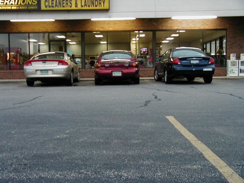 Rear view of three sedans parked in front of a cleaners