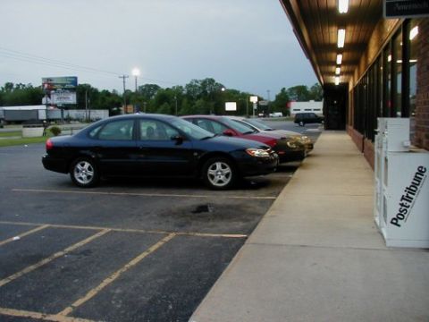 1997 Ford Taurus - A dark blue 1997 Ford Taurus is parked next to a building with other cars in the background.