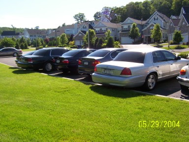 1999 Ford Crown Victoria - Several cars are parked in a lot, with a silver Ford Crown Victoria prominently in the foreground.