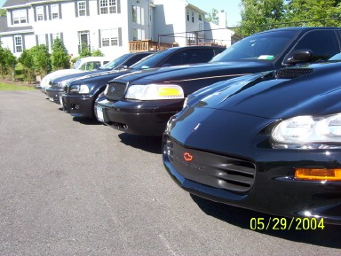 1999 Ford Crown Victoria - Multiple vehicles parked in a lot, with a black Chevrolet Camaro prominent in the front.