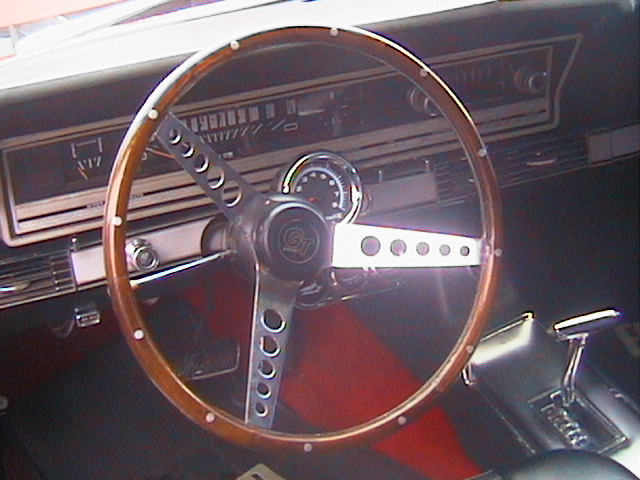 1966 Ford Fairlane interior showing wood steering wheel, dashboard gauges, and center console