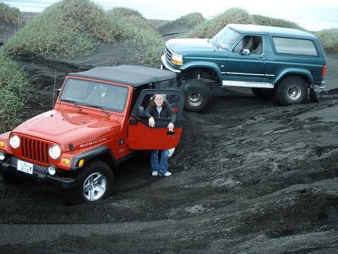 1996 Ford Bronco - A teal Ford Bronco is parked on a dark, sandy hill next to a red Jeep.