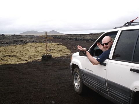 1996 Ford Bronco - A man gestures from the window of a white Jeep Grand Cherokee in a desolate, rocky landscape.